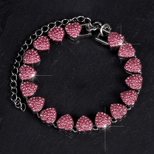 Dettaglio macro del bracciale a cuore in argento con strass rosa su pietra nera