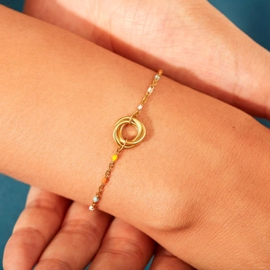 Detail of three-ring interlaced gold bracelet with colorful enamel beads on model wrist