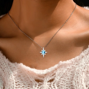Close-up of S925 silver star necklace featuring a blue gemstone and zircons on a model
