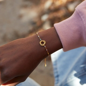 Macro view of gold three-interlocking rings bracelet with colorful enamel beads