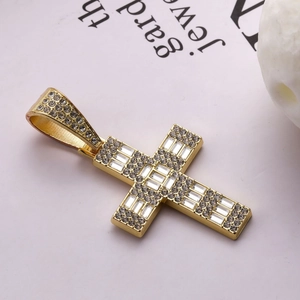 Détail d'un pendentif croix dorée avec zircons baguettes et ronds sur fond magazine
