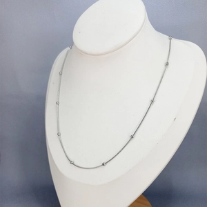 Detail view of silver snake chain necklace with small polished metal beads on neck form