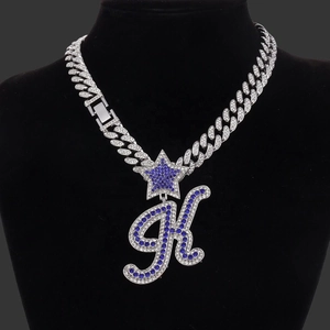 Macro shot of silver hip-hop necklace with blue rhinestone K pendant and star detail