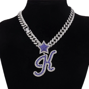 Icy silver Cuban chain with blue rhinestone letter K pendant on a black bust