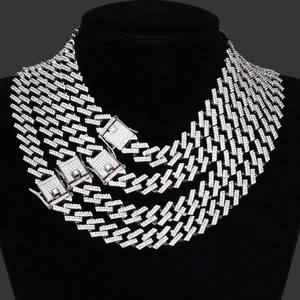 Detail van gelaagde zilveren cuban link kettingen met ruitvormige gespen op een buste