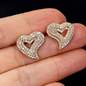 Macro detail of gold-plated open heart earrings encrusted with sparkling cubic zirconia