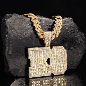 Macro detail of iced out gold KO letter pendant with cubic zirconia on cuban chain