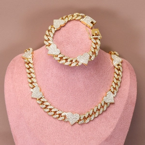 Detail of gold Cuban link chain set with heart pendants and sparkling white zircons