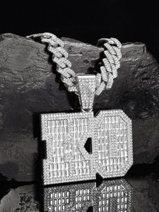 Detail of hip hop ED letter pendant with baguette stones and iced out Cuban chain