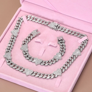Close-up of iced out Cuban link jewelry set with heart charms in a pink velvet box