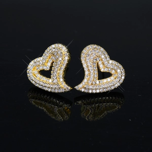 Macro view of heart-shaped earrings with white zircon pavé setting on black background