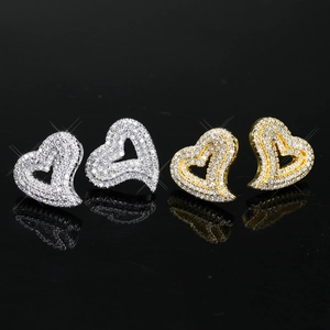 Close-up of heart-shaped stud earrings in gold and silver with cubic zirconia inlays