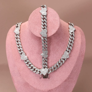 Detail of iced out silver Cuban link necklace and bracelet set with heart charms