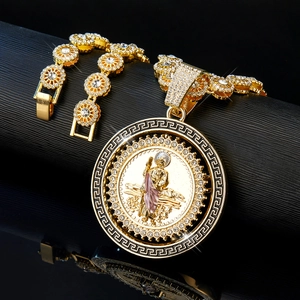 Détail du médaillon Saint Jude et chaîne hip hop sertis de strass brillants sur fond noir