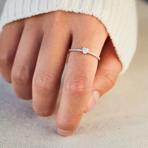 Détail d'une bague en argent S925 avec diamant en forme de cœur portée par une femme