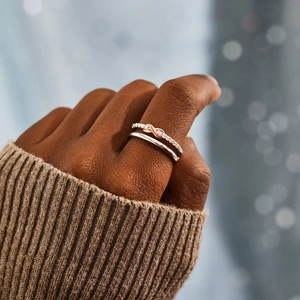 Close-up of stacked S925 silver infinity rings with rose gold detail and pave zircons