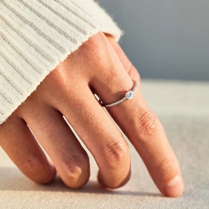 Gros plan d'une élégante bague en argent S925 en forme de cœur portée par un modèle