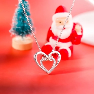 Detail of s925 silver double heart necklace with zircon on red Christmas background