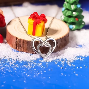 Detailed view of silver infinity double heart pendant with crystals on festive snow backdrop