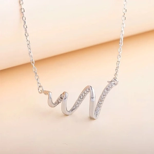 Macro shot of s925 silver wavy pendant featuring micro-pave cubic zirconia on cross chain