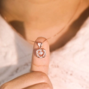 Détail du pendentif cœur en argent s925 avec pierre dansante sur le cou d'une femme