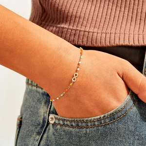 Gold s925 silver infinity bracelet with colorful enamel beads on a woman's wrist