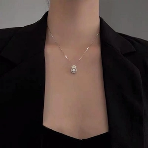 Silver crown heart pendant necklace shown on a model with a black blazer and background