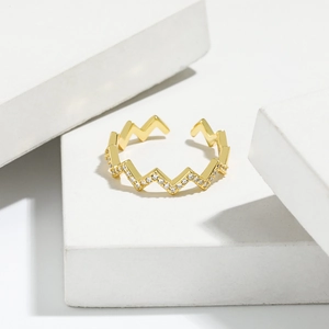 Minimalist gold wave ring with pavé zircon accents on white geometric displays
