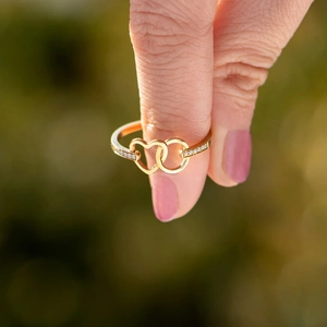 Polished gold s925 sterling silver ring featuring interlocking hearts and cubic zirconia