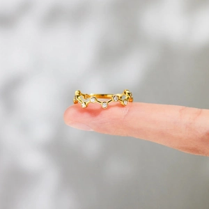 Gros plan d'une bague délicate en argent S925 doré avec zircons portée au doigt