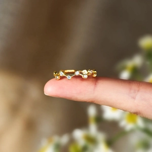 Détail macro d'une bague vague dorée ornée de zircons brillants à chaque courbe