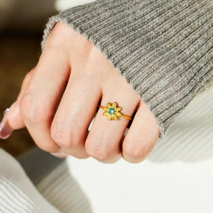 S925 sterling silver sunflower ring with blue gemstone on hand against knit background