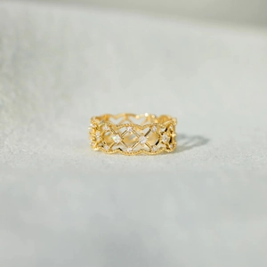 Détails macro de la bague en maille dorée avec incrustations de zircons sur fond de tissu