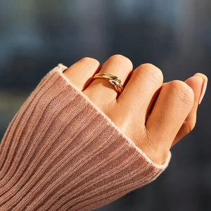 Gros plan de bagues entrelacées tricolores en or argent et or rose sur la main d'un modèle