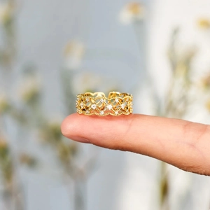 Détail d'une bague en maille dorée avec pierres en zircon et bords perlés