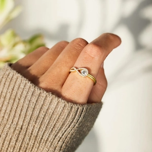 Gros plan d'une bague infini dorée avec diamants sur une main et un pull en maille