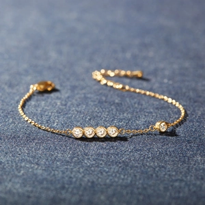 Minimalist S925 sterling silver gold bracelet with five round zirconia stones on blue fabric