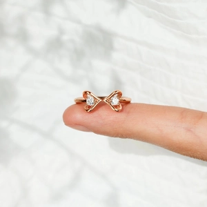 Détail d'une bague ajustable en or rose avec double cœur en zircon sur fond blanc pur