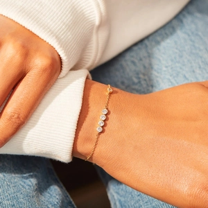 Minimalist gold chain bracelet with four bezel-set round cubic zirconia worn on a wrist