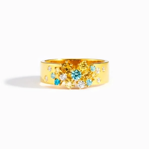 Bague large dorée ornée de pierres précieuses colorées sur fond blanc épuré