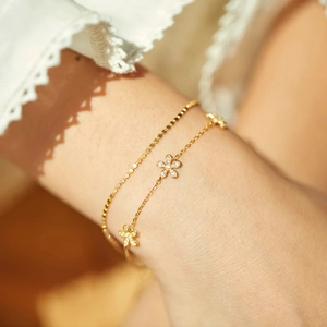 Détail du bracelet double couche doré avec fleurs de marguerite et zircons scintillants
