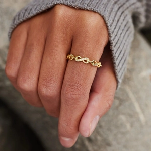 Detailed view of a gold infinity link ring with sparkling white zircon inlays on hand