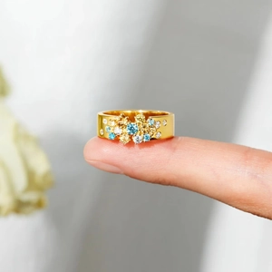 Vue macro d'une bague dorée ornée de pierres précieuses colorées sur un anneau large