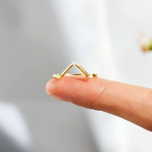 Macro detail of V-shaped gold ring with three white opal stones on a model's finger