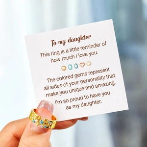 Gros plan sur une bague dorée avec zircons colorés et carte cadeau pour fille bijoux