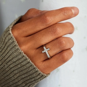 Macro detail of S925 sterling silver cross ring with sparkling zircon inlays on finger