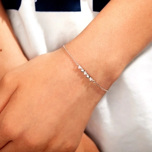 Detail of S925 sterling silver heart bracelet with alternating zircon and polished charms