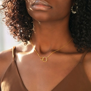 Detail of gold-plated geometric necklace showing interlocking circle and square pendant