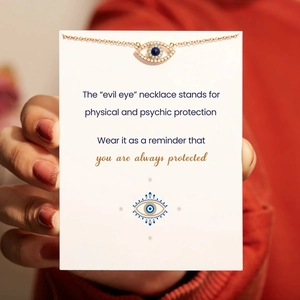 Detail of s925 silver evil eye pendant with blue zircon on a gold chain with gift card