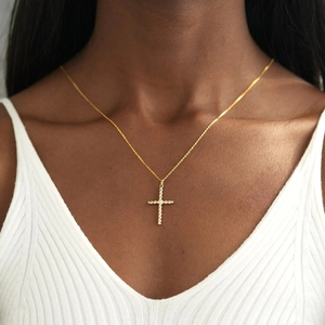 Élégant pendentif croix torsadée bicolore en or et argent porté par un mannequin femme